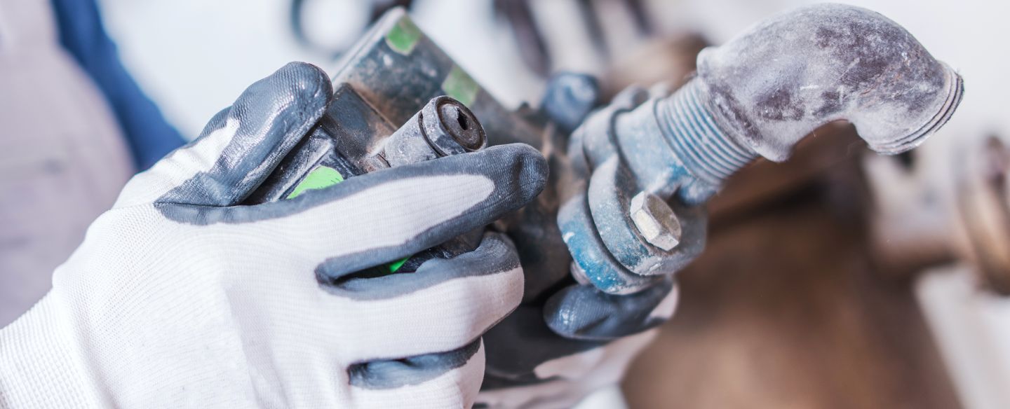 plumber with hydraulic system part in hand gray me